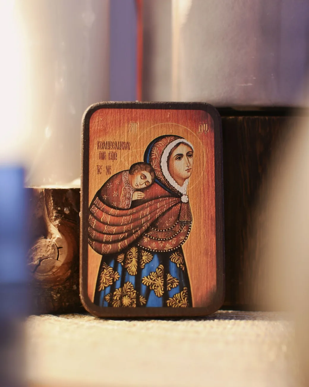 Icono de pequeño formato sobre tabla de madera, con fondo cálido y ornamentos dorados en las vestiduras